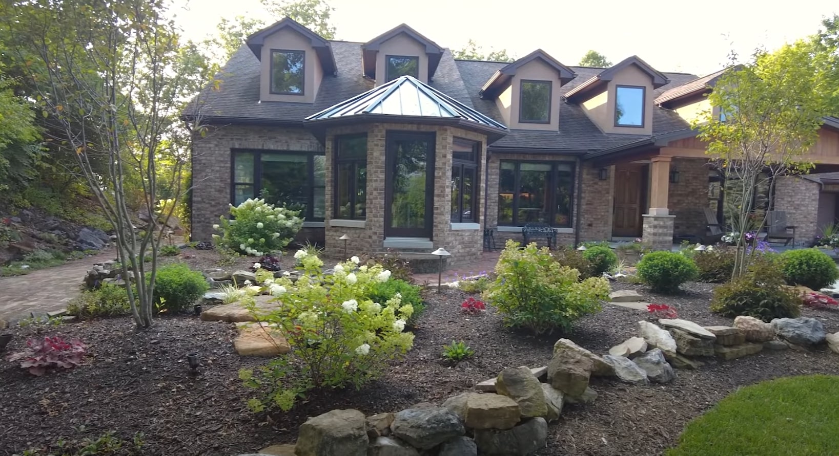 Luxury home front yard with natural stone landscaping, decorative plantings, and mature shrubs
