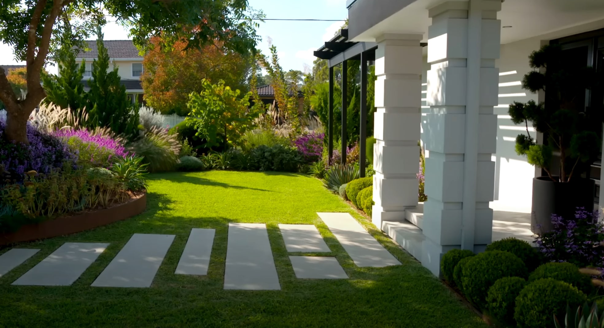 Beautiful modern landscape design with lush green lawn and colorful plantings in Jurupa Valley